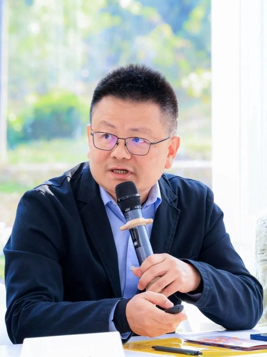 深圳市文化创意与设计联合会里的常务副秘书长徐挺，朝着参会代表去介绍新锐奖的情况，。